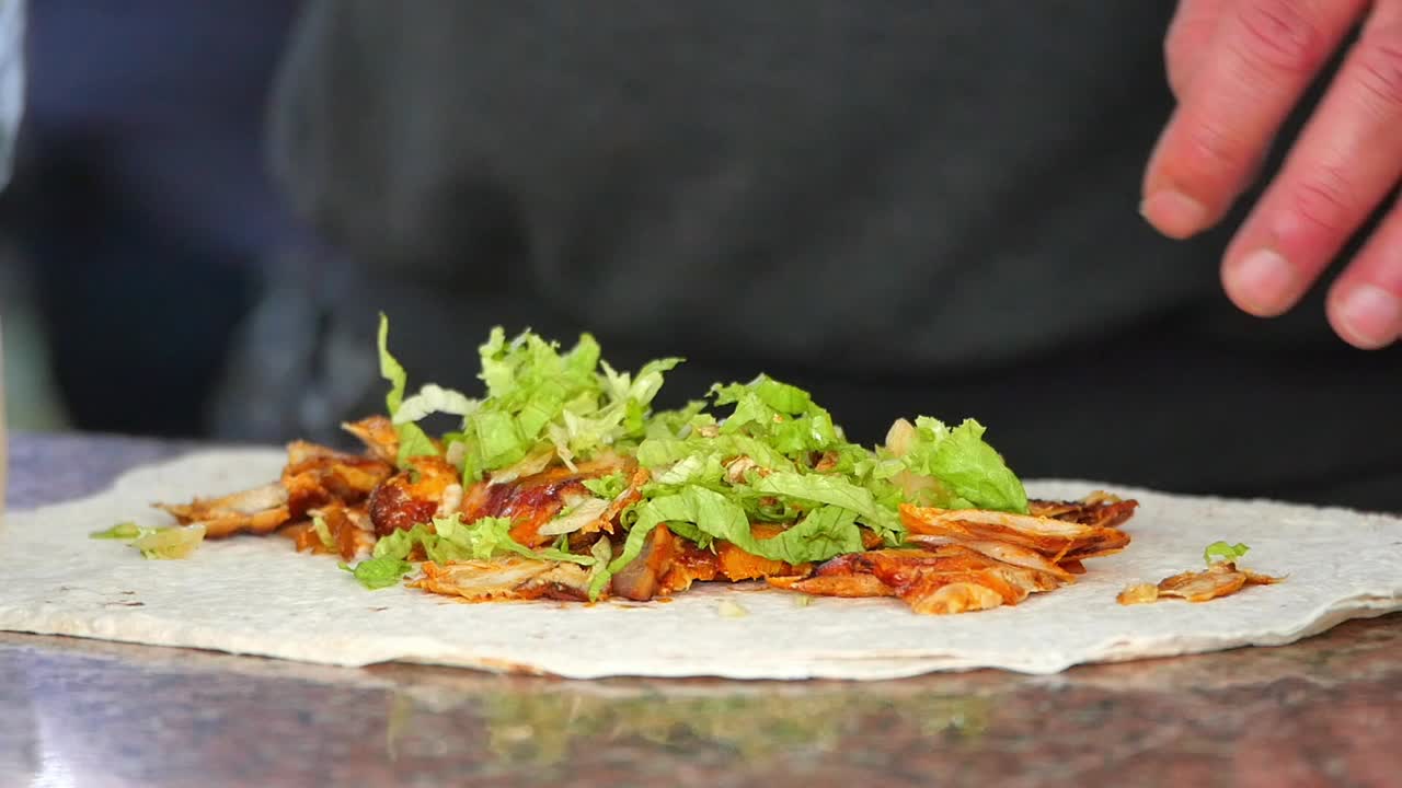Preparing a delicious kebab wrap with meat and salad