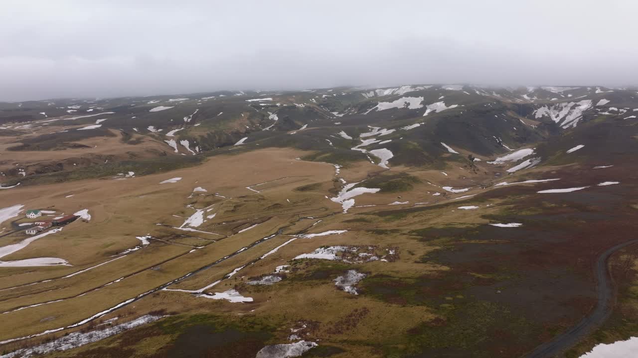 Veduta aerea del paesaggio montano con neve che si scioglie, in una giornata nuvolosa e nebbiosa, Islanda.
