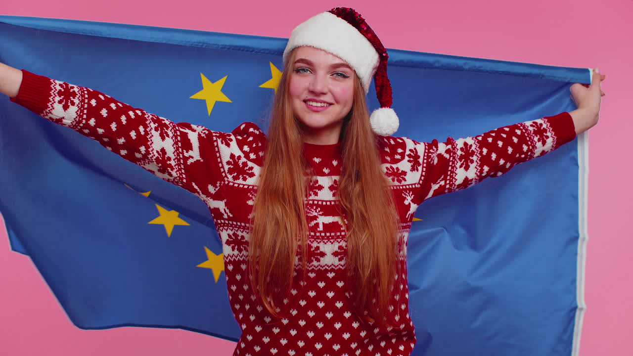 Ragazza natalizia che sventola la bandiera dell'Unione Europea, sorridendo e acclamando i diritti umani democratici e le libertà dell'Europa.