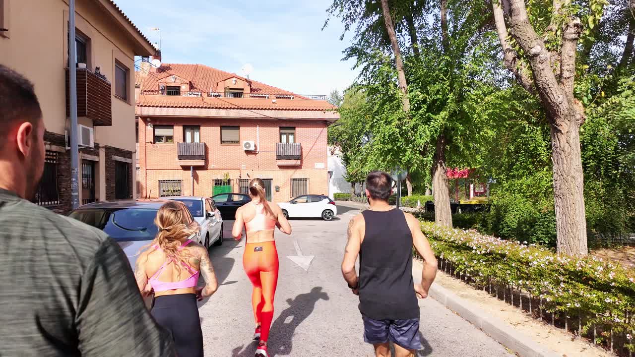 Gruppo di persone che corrono lungo una via residenziale in una giornata di sole