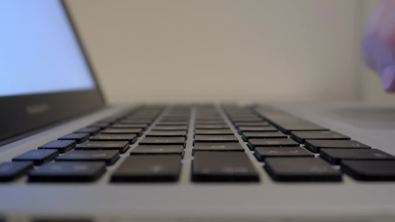 hands typing on laptop keyboard, close-up shot from left side and nice depth of field