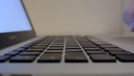 manos escribiendo en el teclado del portátil, primer plano desde el lado izquierdo y buena profundidad de campo