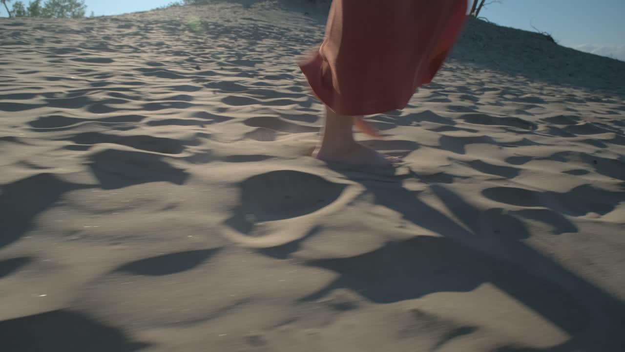 Close up of a woman walking in the sand in a long skirt barefoot in the beautiful sun light in Sandbanks, Ontario, Canada