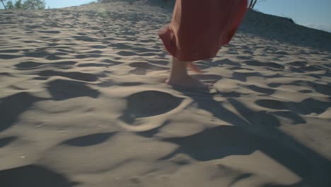 close up of a woman walking in the sand in a long skirt barefoot in the beautiful sun light in sandbanks, ontario, canada