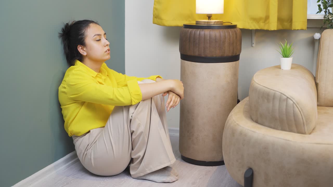 우울한 젊은 여성. 벽  ⁇ 에 앉아 있습니다.