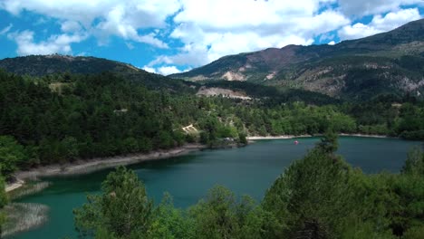 Crane-lift-up-reveal-shot-of-Lake-Tsivlou-with-mountains-surrounding-peacefully-the-natural-waters-on-an-overcast-cloudy-day