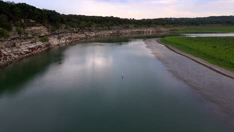 aerial scenic view flying over calm water with cloud reflection in canyon lake during dusk in texas
