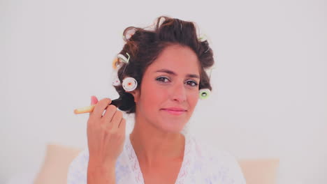 content woman in hair curlers applying powder