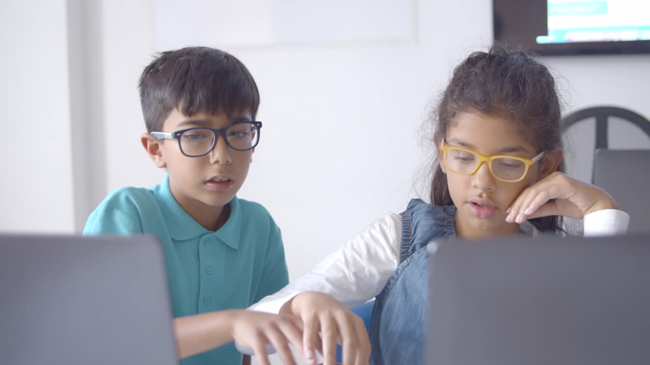 niño y niña con gafas colaborando en un proyecto de clase