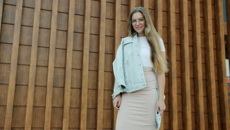 young woman in stylish outfit posing in front of a wooden wall