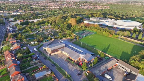 Aerial-descend-tilt-up-reveals-empty-soccer-field-behind-school-in-suburban-neighborhood