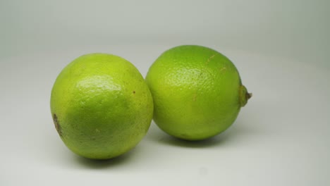 two green sour lemons moving in circular motion - close up shot