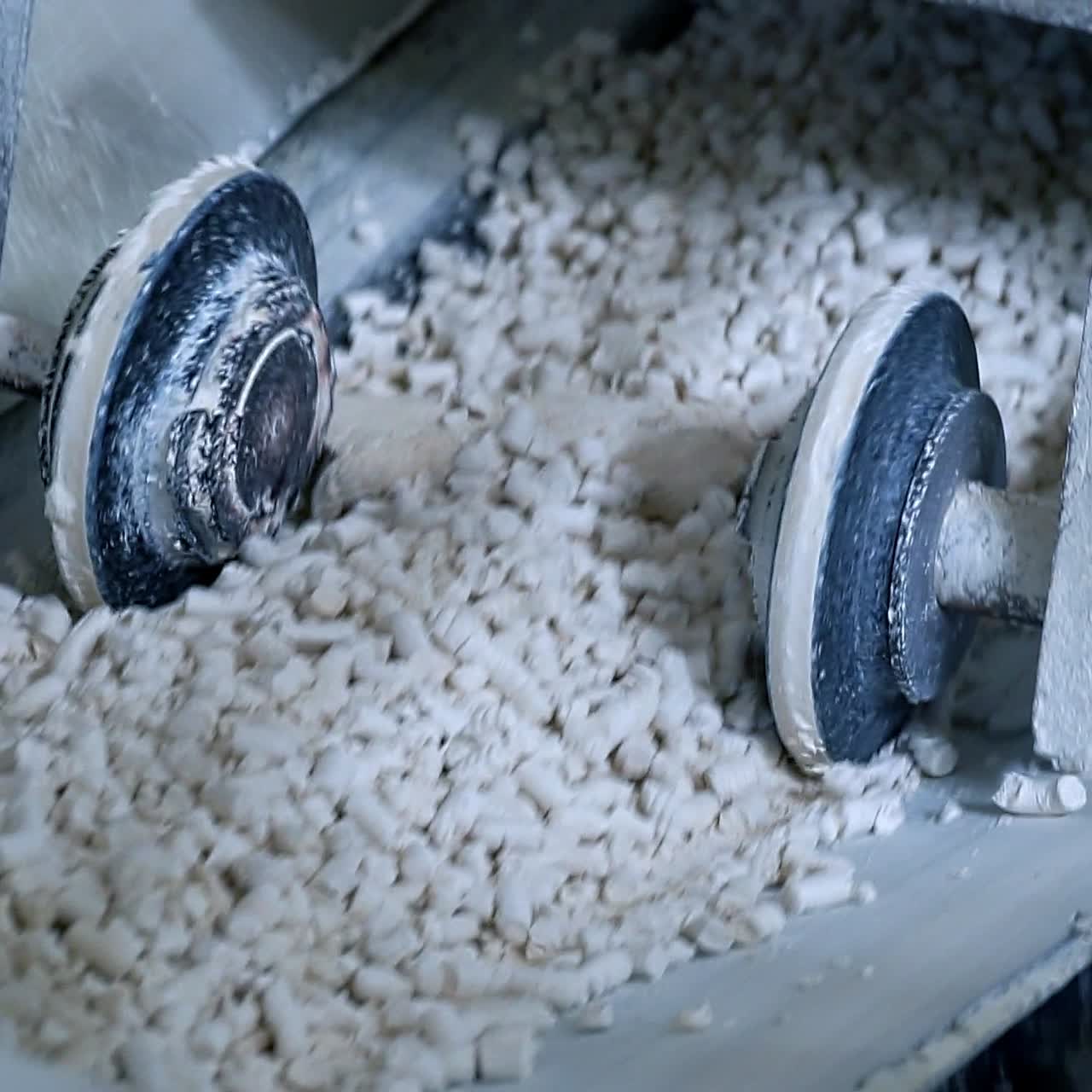Two wheels moving along both sides of conveyor belt. Line transporting pressed kaolin clay. Close up