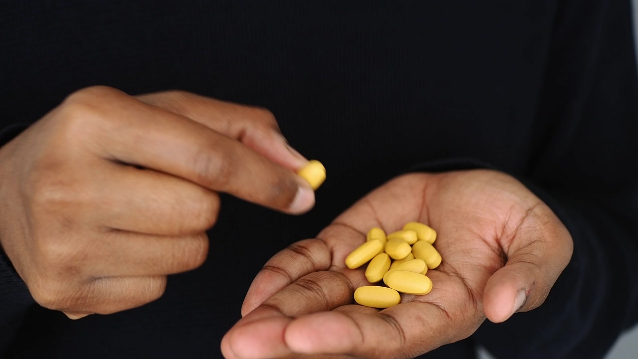A Person's Hand Holding and Picking Up Yellow Pills