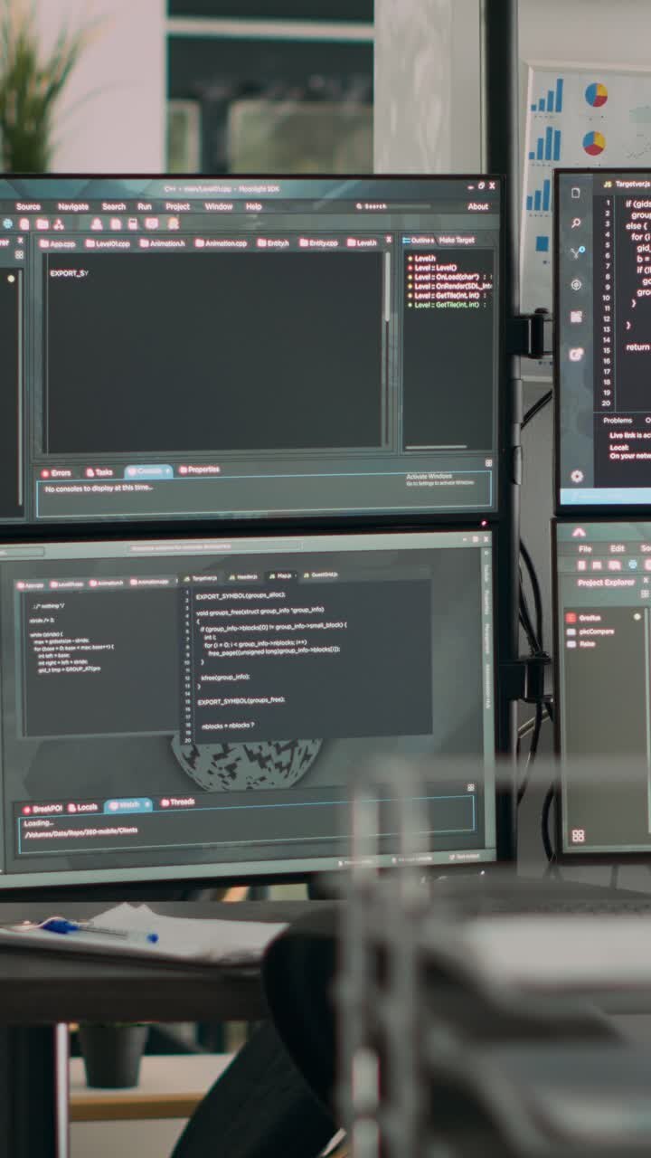 Lodret video: Skærme viser fortolkningskode på et tomt it-bureaukontor med computere på skrivebordet