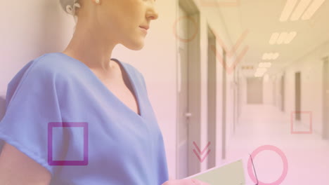 in hospital corridor, healthcare professional in blue scrubs holding documents
