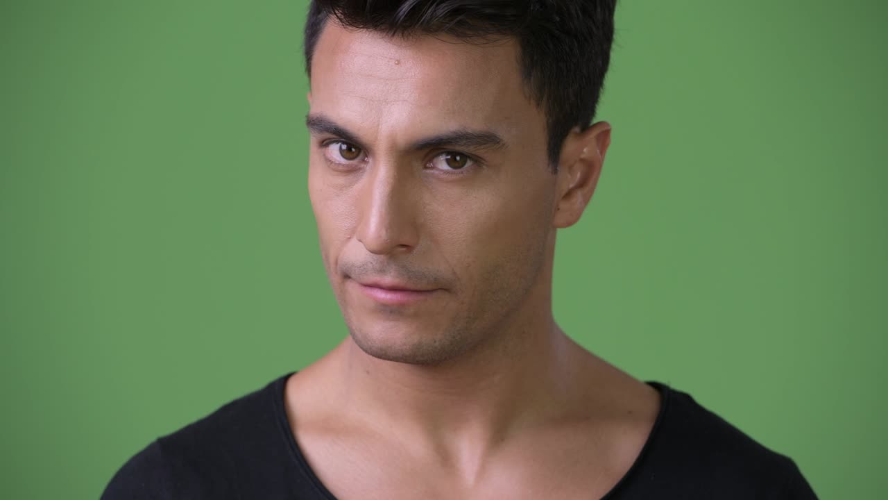 Giovane e bel uomo ispanico su sfondo verde.