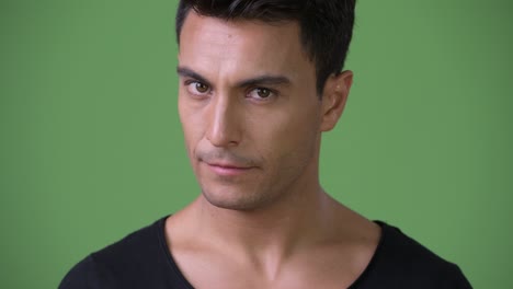 young handsome hispanic man against green background
