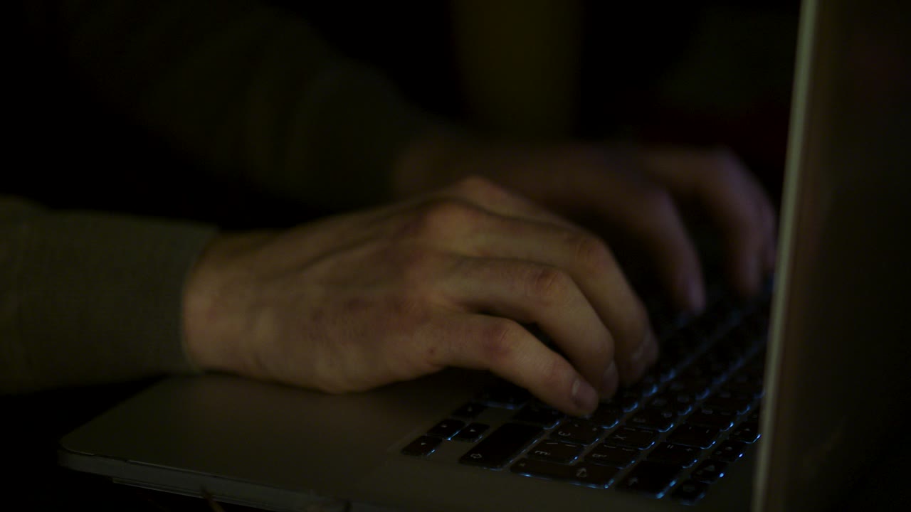 persona che scrive sul portatile di notte
