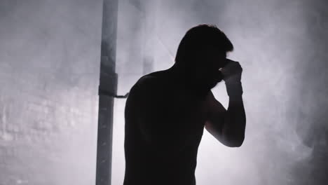 sportsman boxing in darkness in gym