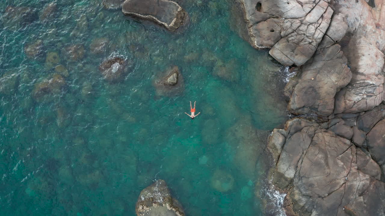 Aerial - Man Floating on back on Surface of Turquoise Ocean Water