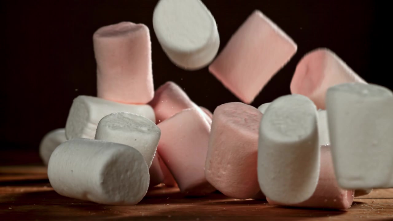 Marshmallow che cadono al rallentatore su un tavolo di legno