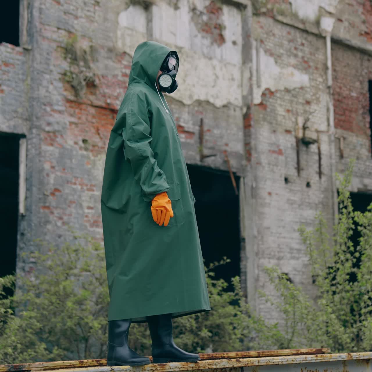 Man in protective mask on ruins. Dramatic portrait of man wearing gas mask near ruined building