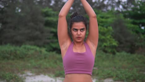 indian sportswoman doing praying hands warm up exercise routine in nature