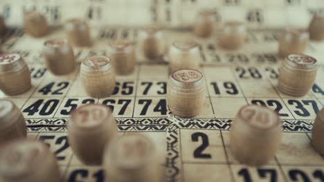 video macro de un tablero de bingo, luces de estudio, 120 fps, cámara lenta, dígitos de chips de madera, imágenes en bruto, juego de mesa de lotería, números de cartas, empuje de grúa en movimiento suave