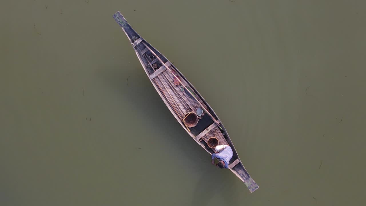 나무 보트의 어부가 물고기를 잡기 위해 미끼와 그물을 준비합니다.