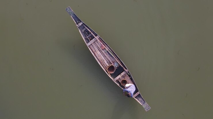 Un pescatore su una barca di legno prepara esche e reti per la pesca