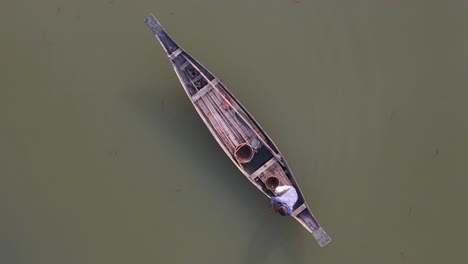 a fisherman in a wooden boat prepares baits and nets for catching fish