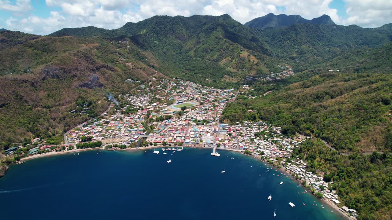 Aerial Drone Footage Showcases Stunning Pitons Bay In St. Lucia, Revealing Vibrant City Views And Lush Green Hills. The Sunny Summer Day Enhances The Picturesque Scenery Of Small Houses, White Boats.