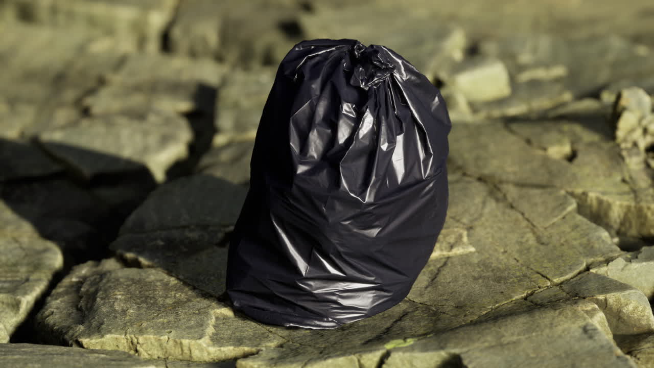 Using a discarded bag on rocky terrain by a peaceful waterbody at dusk