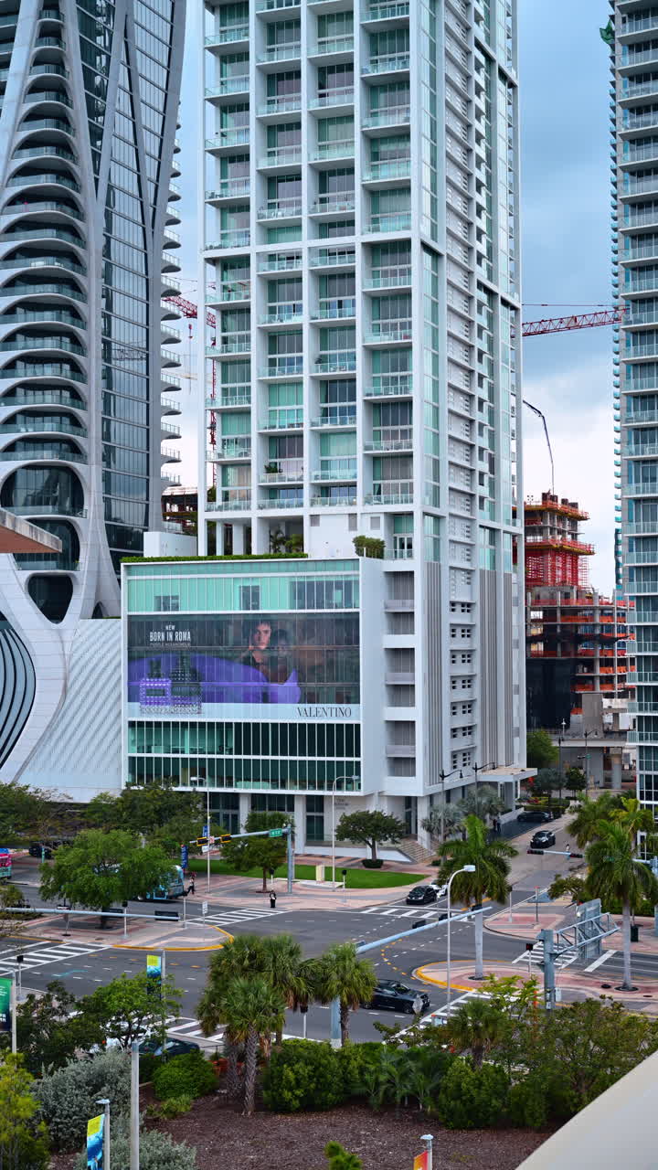 Miami, USA, 16 aprile 2026: Architettura moderna di grattacieli e vista stradale nel centro di Miami. Vista dall'alto di lussuosi condomini, pubblicità di Valentino e incrocio con palme.