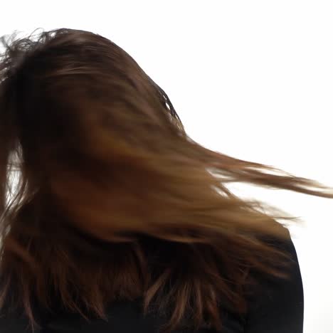 a charming girl with natural hair is waving her head to the sides on a white background in the studio. woman is posing by her long hair