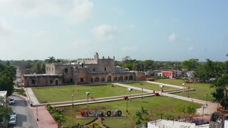 Revealing-medieval-brick-building-of-Convent-of-San-Bernardino-de-Siena.-Large-old-building-and-green-park-in-front.-Valladolid,-Mexico