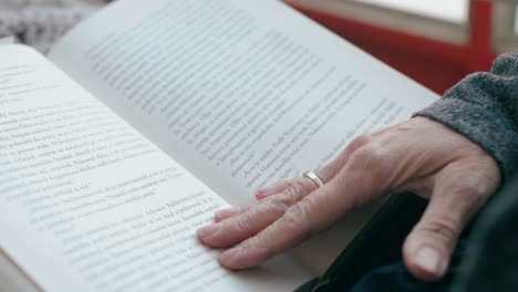 primer plano de la mano de una mujer pasando una página mientras lee un libro