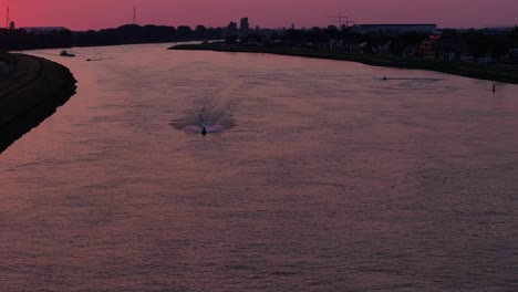 silhouettes of jet-ski riders on the river noord, rotterdam at sunset, aerial