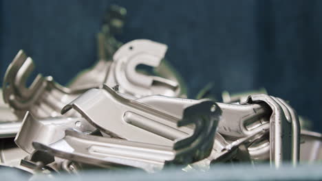 Close up of a pile of car parts falling off the production line after being pressed into shape by a big hydraulic press in the automated production line