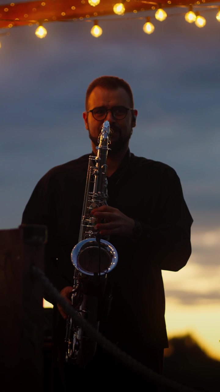 Uomo che suona il sassofono in silhouette contro un cielo al tramonto
