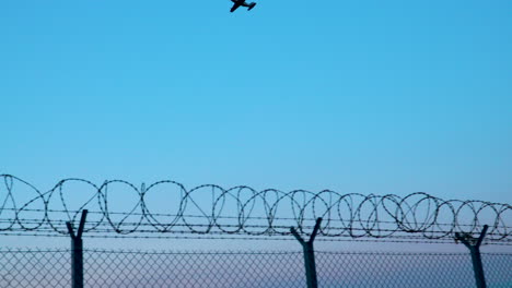 avión volando en el cielo azul con una valla de alambre de púas en el aeropuerto chopin de varsovia