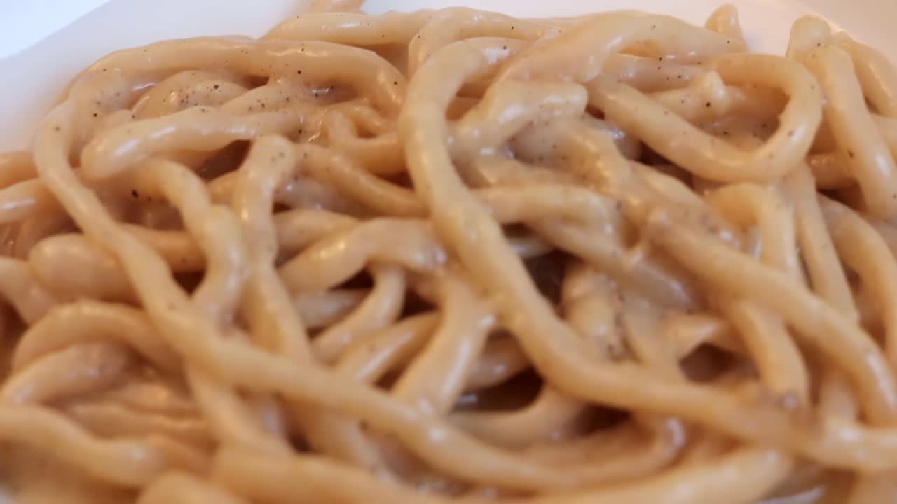 primer plano de fideos pici caseros con salsa cacio e pepe