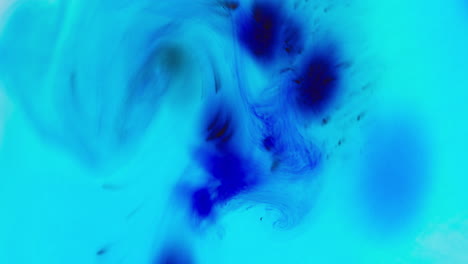 turquoise and blue paint or dye dropped into water against white background to create swirling colourful smoke background