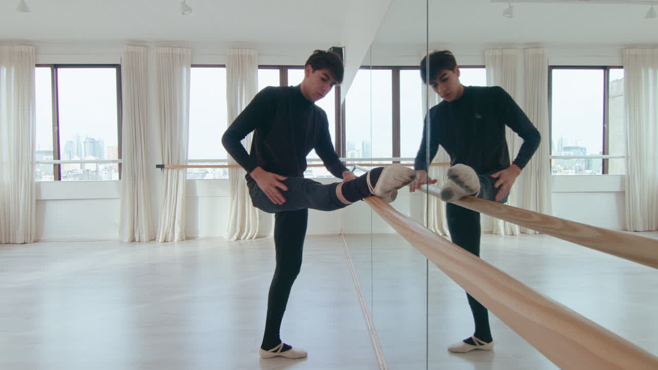 Male Ballet Dancer Stretching Hamstring at the Barre in Studio