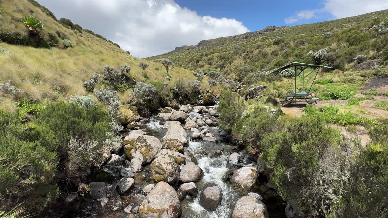 river flowing next to a shed in a valley in mount Kenya