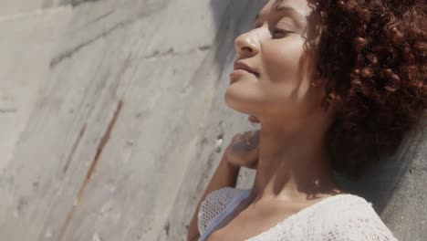 vista lateral de una joven mujer afroamericana relajándose en la playa bajo el sol 4k