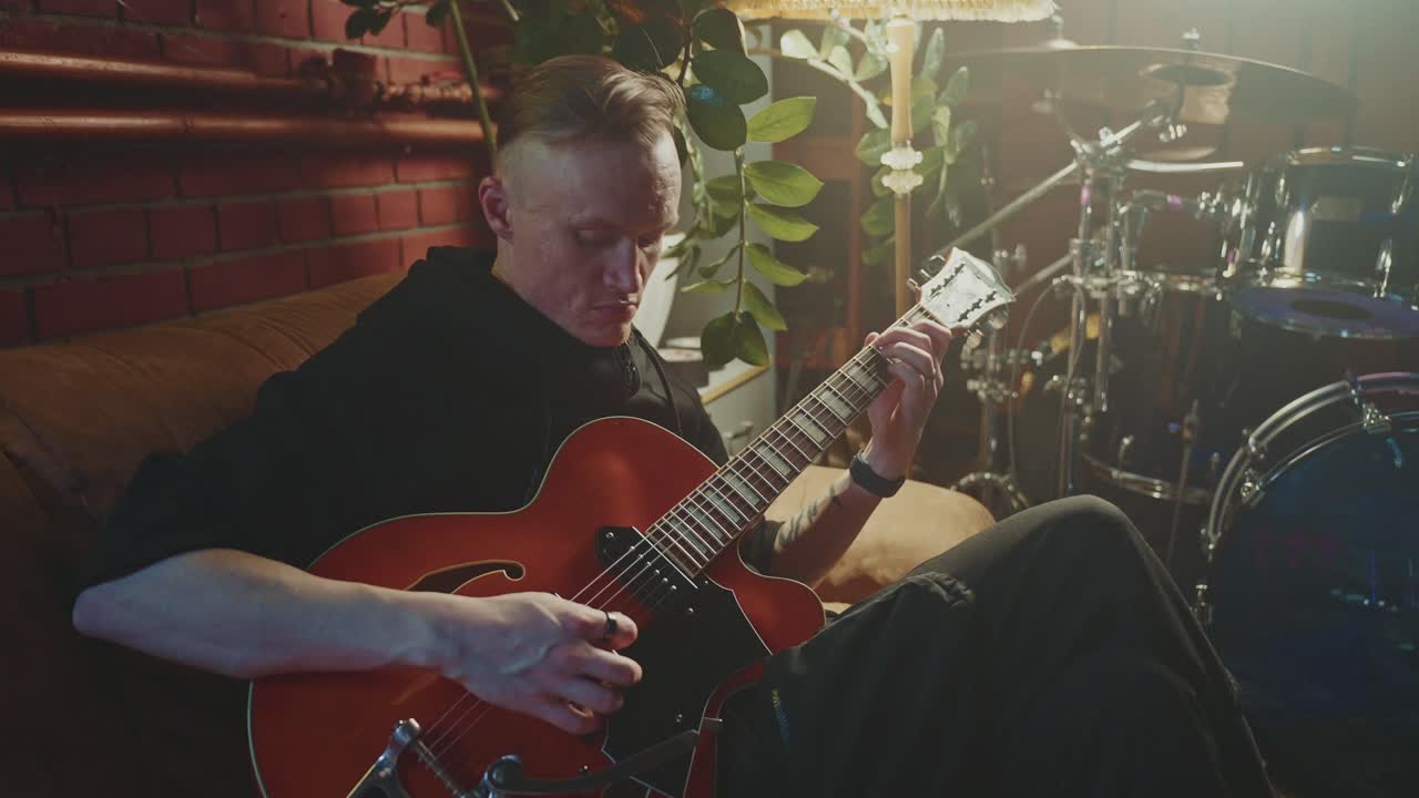 Mand spiller rød elguitar i et musikstudie