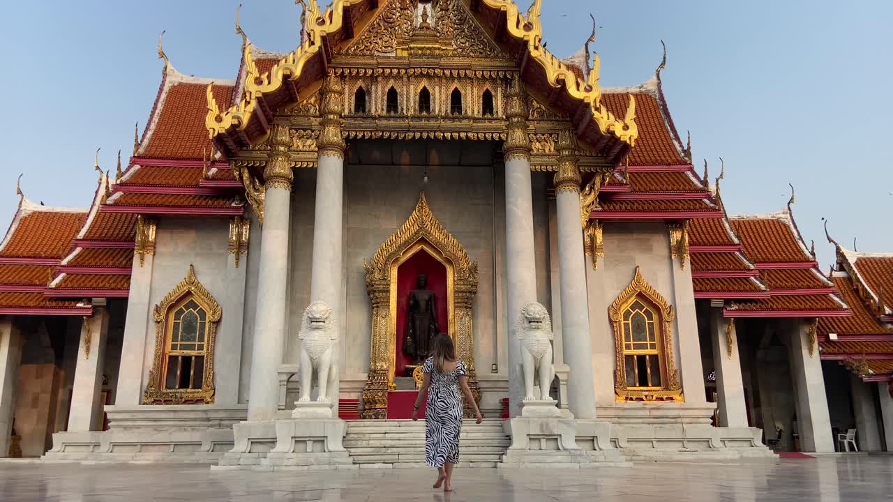 una chica rubia caucásica caminando hacia el templo thai wat benchamabophit