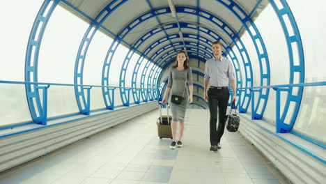 a man and a woman go with luggage at the terminal of the station or airport